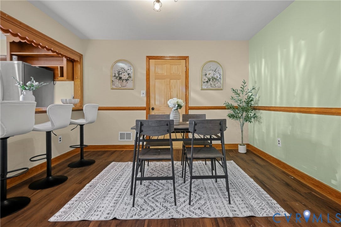 9834 N Wagstaff Circle, Mechanicsville, VA 23236 Dining area featuring wood-finish flooring, wood-toned chair rail molding, a pass-through opening with decorative wood trim, and a six-panel wood door