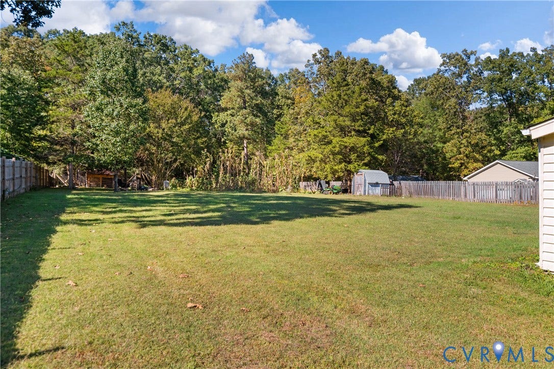 9834 N Wagstaff Circle, Mechanicsville, VA 23236 Expansive backyard featuring a large grass lawn, perimeter wooden privacy fencing, and dense mature tree line