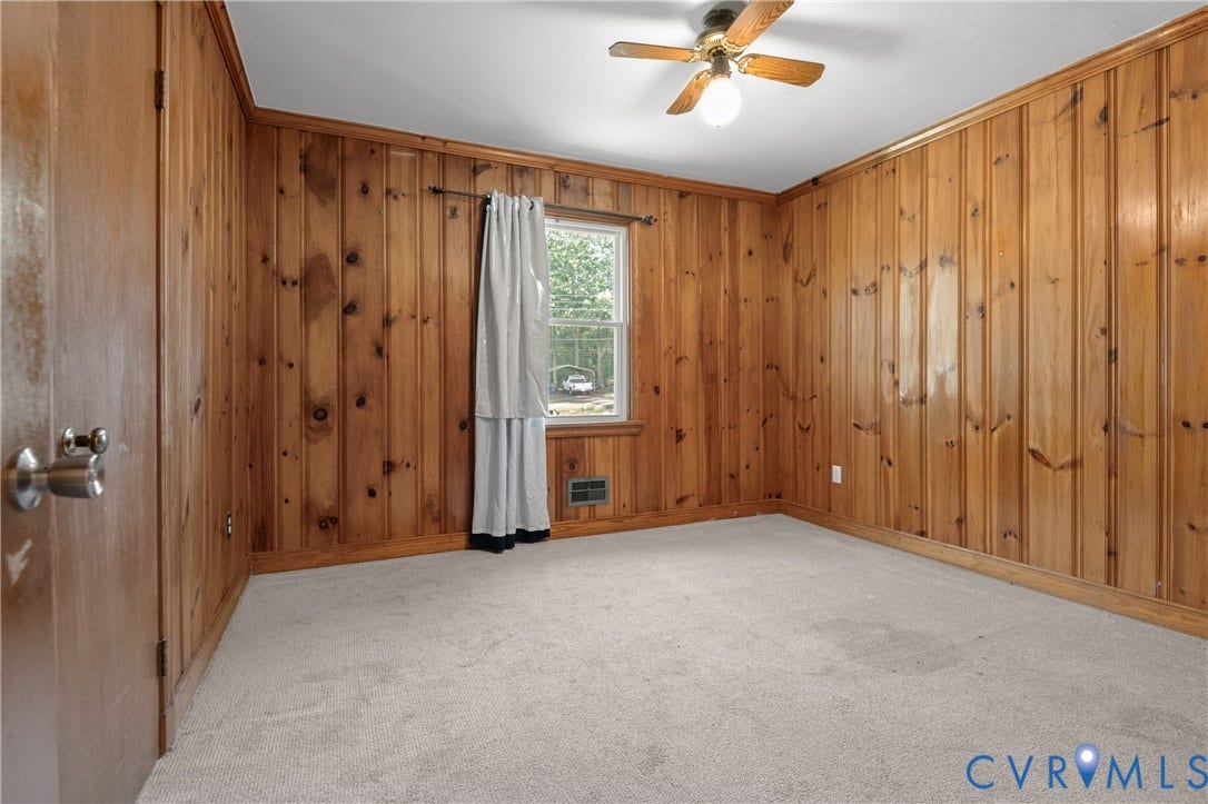 9834 N Wagstaff Circle, Mechanicsville, VA 23236 Room featuring natural wood-paneled walls, carpeted flooring, a single-hung window, and a central ceiling fan with an integrated light fixture