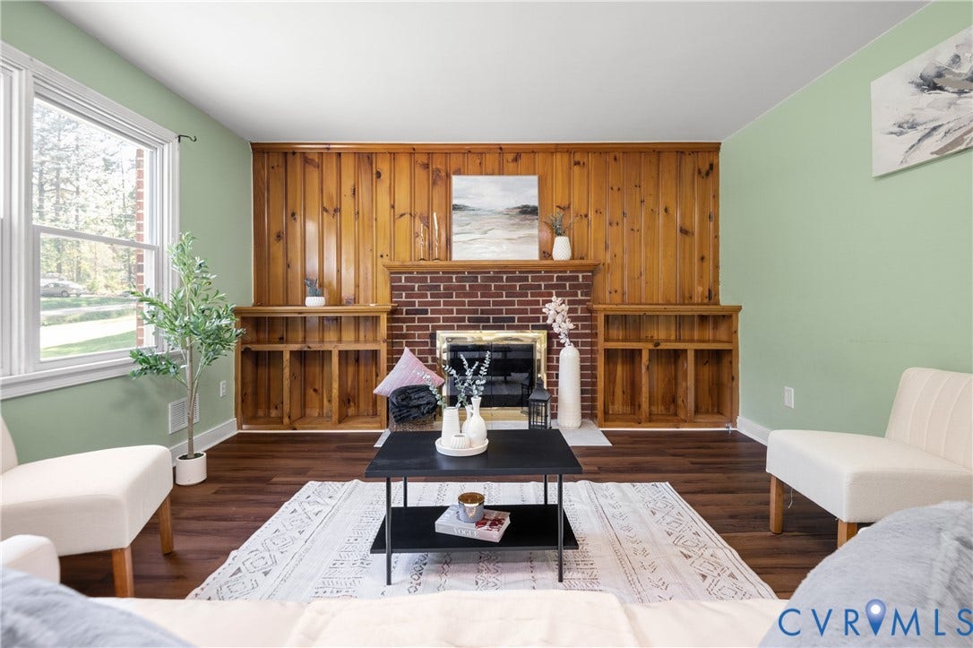 9834 N Wagstaff Circle, Mechanicsville, VA 23236 Brick fireplace with wood mantel, vertical wood paneling, and built-in shelving, complemented by wood-finish flooring