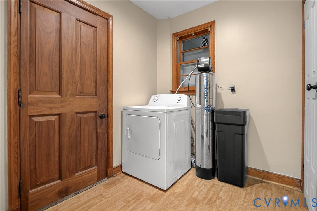 9834 N Wagstaff Circle, Mechanicsville, VA 23236 Utility area featuring a water softening system, wood-finish flooring, solid-core wood-style door, and a multi-pane window with wood trim