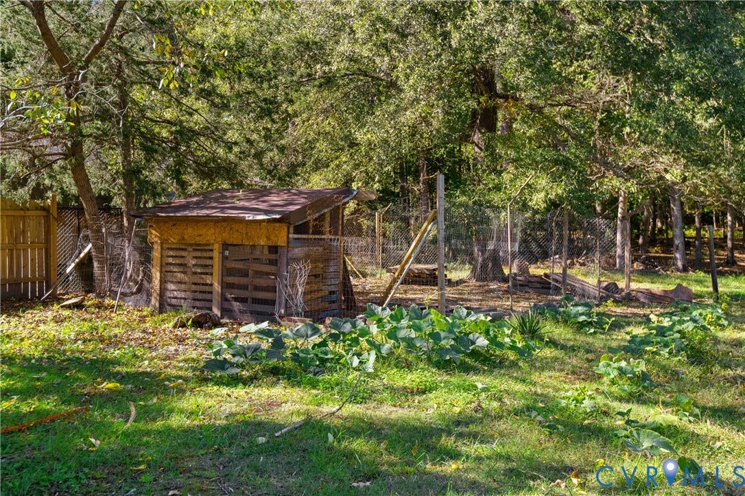 9834 N Wagstaff Circle, Mechanicsville, VA 23236 Outdoor structure with wood-slat siding, chain-link enclosure, and surrounding garden space set within a wooded lot