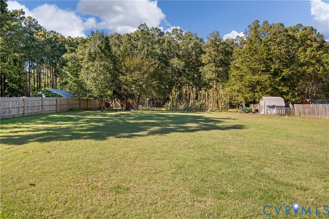 9834 N Wagstaff Circle, Mechanicsville, VA 23236 Expansive backyard featuring an open grass lawn, wood-panel fencing, and mature tree line
