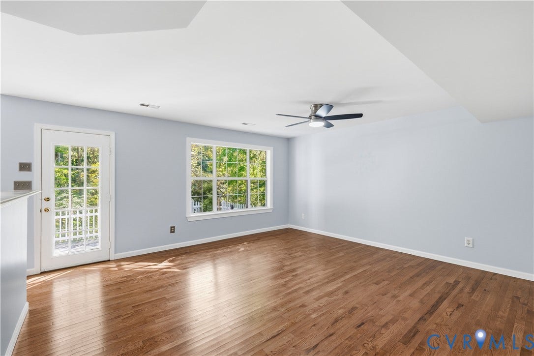 7652 Thacher Drive, Toano, VA 23168 Spacious interior featuring wood-finish flooring, a multi-pane glass door, large picture window, and a ceiling-mounted light fixture with fan