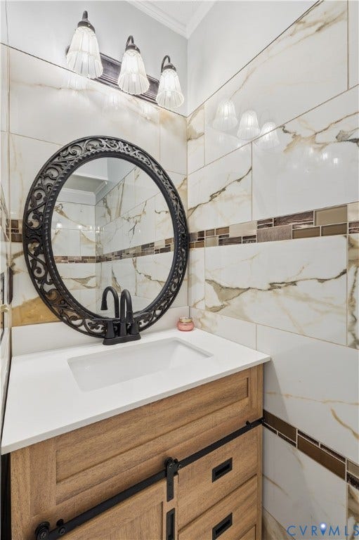 7652 Thacher Drive, Toano, VA 23168 Vanity with wood-finish cabinetry, white countertop, matte black hardware, decorative oval wall mirror, and large-format wall tile with glass mosaic accent detailing
