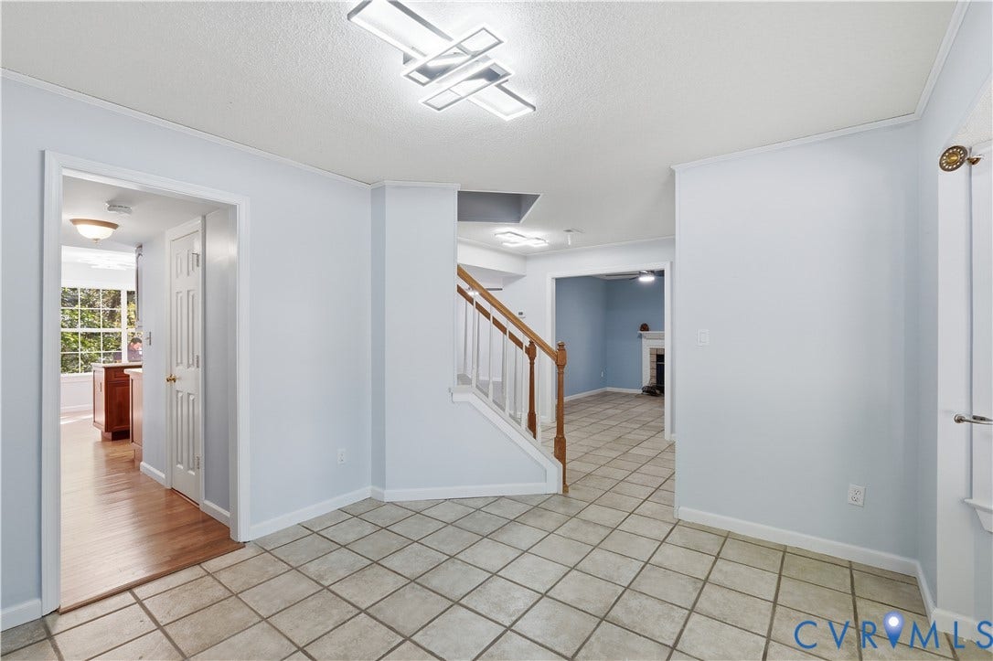 7652 Thacher Drive, Toano, VA 23168 Interior foyer featuring tile flooring, staircase with a wood handrail, and modern geometric flush-mount light fixtures
