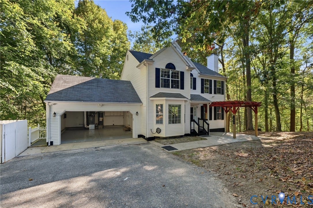 7652 Thacher Drive, Toano, VA 23168 Two-story vinyl-sided exterior featuring an attached two-car garage, a wooden pergola, a bay window, and dark-finished shutters