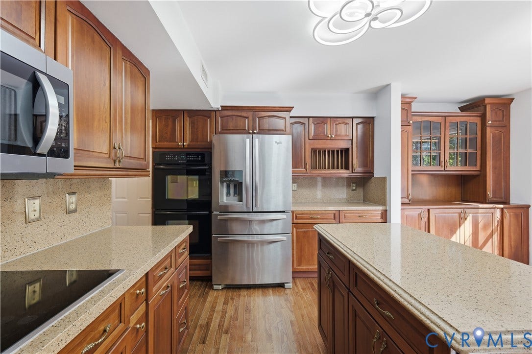 7652 Thacher Drive, Toano, VA 23168 Kitchen featuring wood cabinetry, stone-style countertops, stainless steel appliances including a double wall oven, central island, and wood-finish flooring