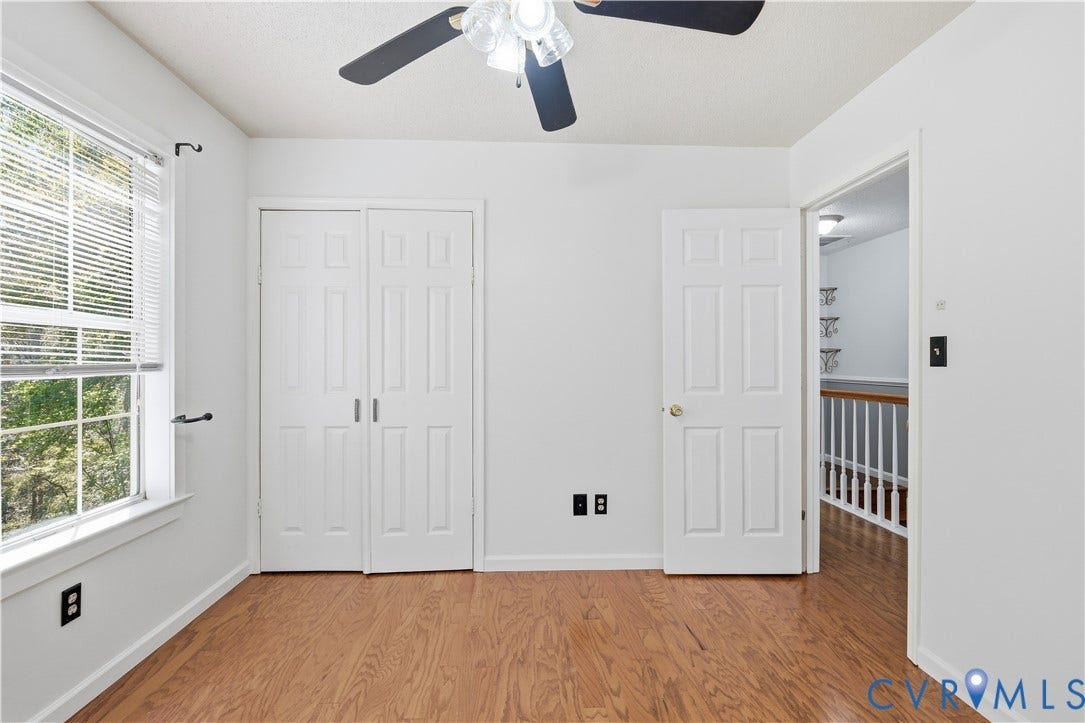 7652 Thacher Drive, Toano, VA 23168 Room featuring wood-finish flooring, a multi-pane window with blinds, bi-fold closet doors, and a ceiling fan with integrated lighting