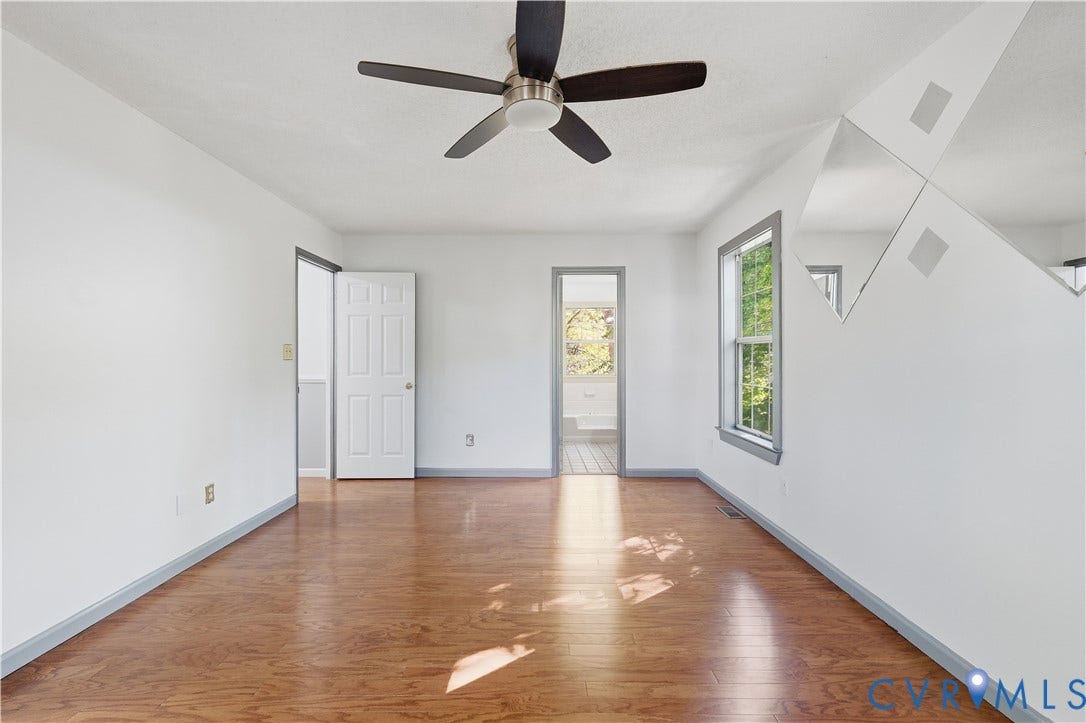 7652 Thacher Drive, Toano, VA 23168 Wood-finish flooring, central ceiling fan with integrated lighting, diamond-patterned wall mirrors, and paneled interior door