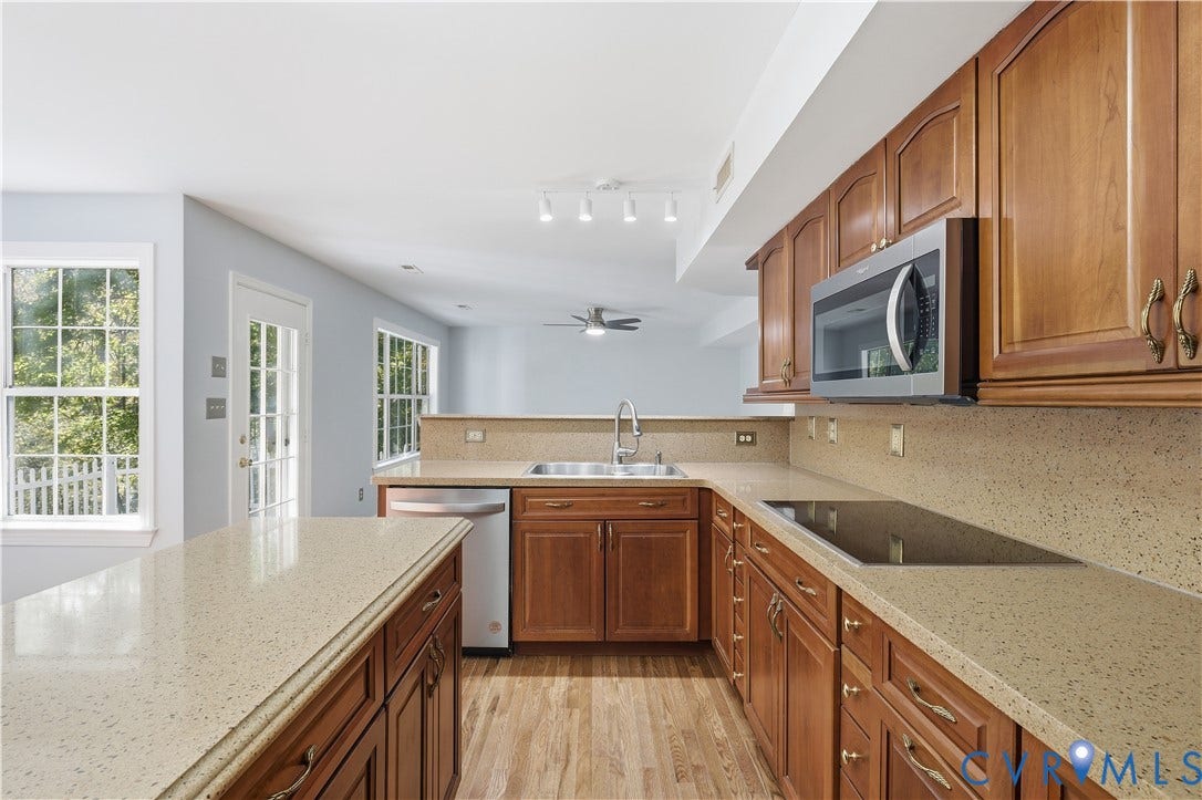 7652 Thacher Drive, Toano, VA 23168 Kitchen featuring wood cabinetry, stone-composite countertops, stainless steel appliances, a peninsula, and wood-finish flooring