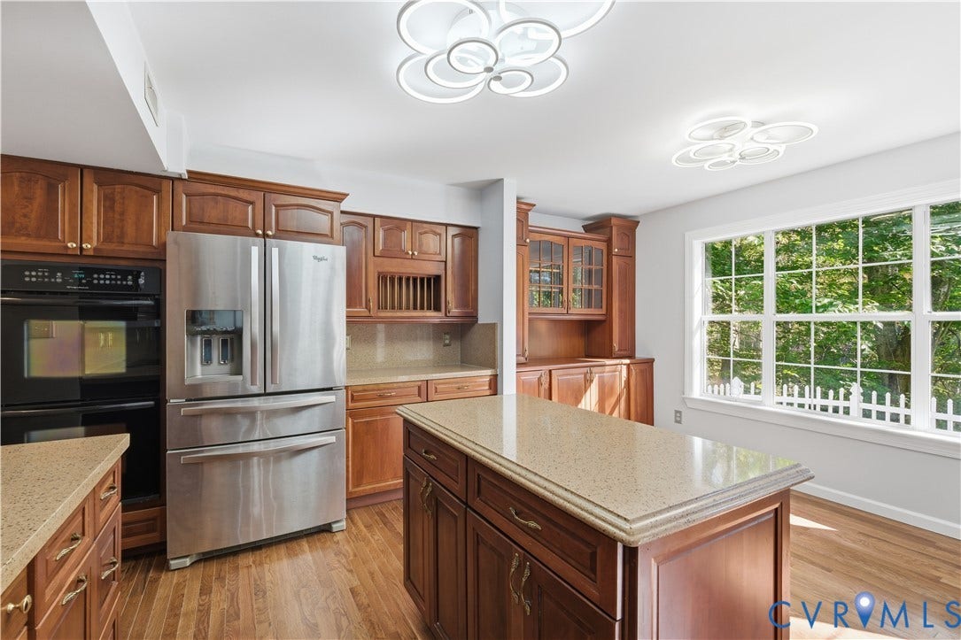 7652 Thacher Drive, Toano, VA 23168 Kitchen featuring wood cabinetry, stone-surface countertops, central island, stainless steel refrigerator, and modern geometric ceiling fixtures