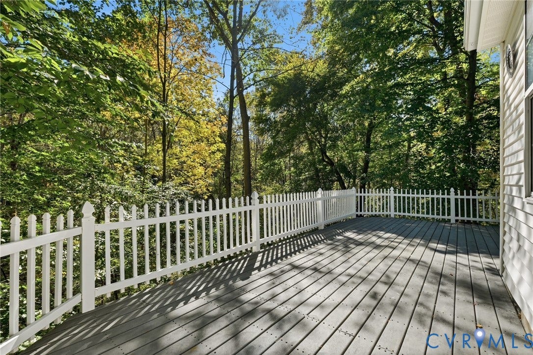 7652 Thacher Drive, Toano, VA 23168 Elevated deck featuring gray composite decking and a white picket-style railing, surrounded by mature trees