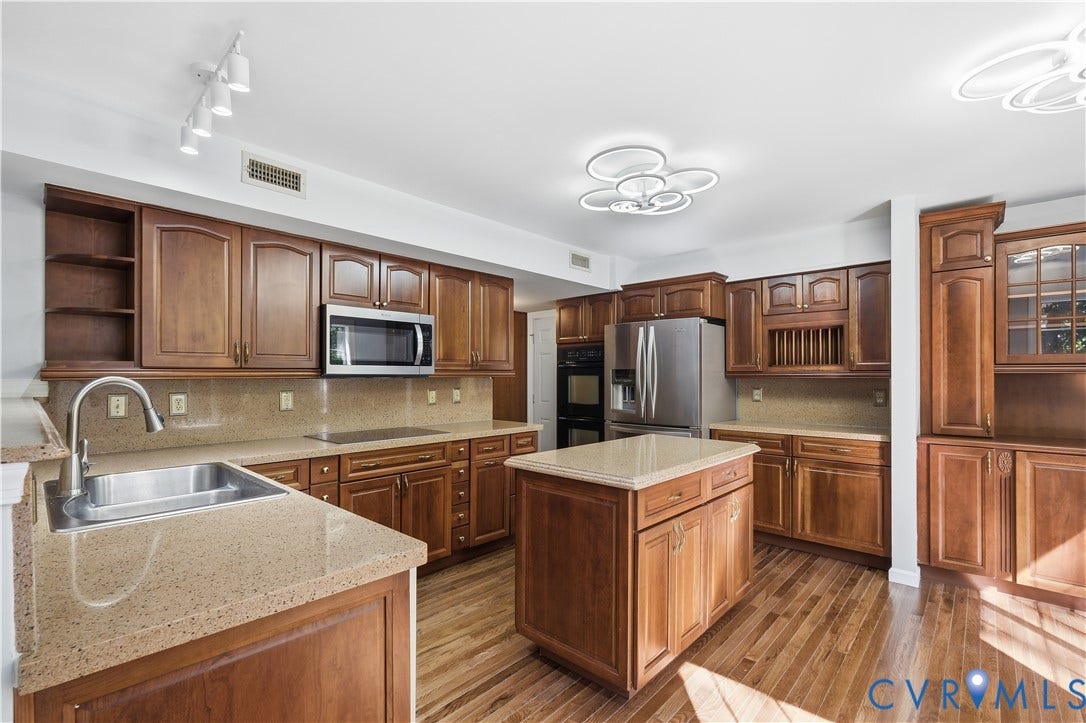 7652 Thacher Drive, Toano, VA 23168 Kitchen featuring stained wood cabinetry, stone countertops, a central island, stainless steel appliances, and wood-finish flooring
