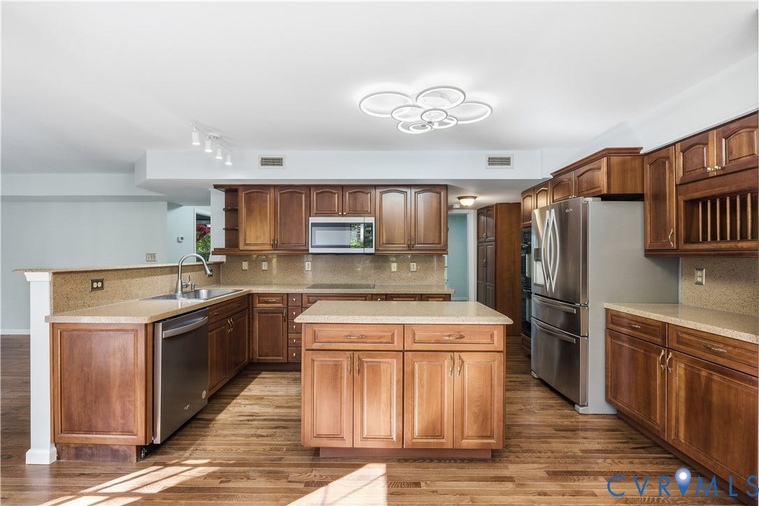7652 Thacher Drive, Toano, VA 23168 Kitchen featuring stained wood cabinetry, stone-finish countertops, stainless steel appliances, central island, and wood-finish flooring