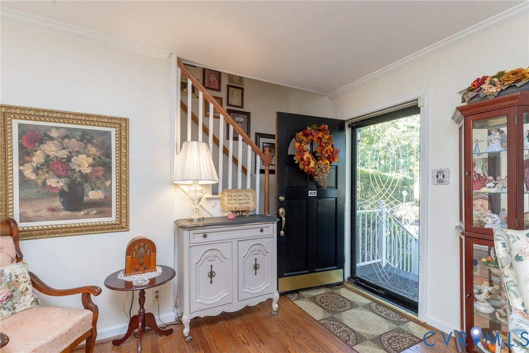 5211 W Grace Street, Richmond, VA 23226 Foyer entry featuring a black front door with a glass storm door, wood-finish flooring, and a staircase with a wooden handrail and white balusters