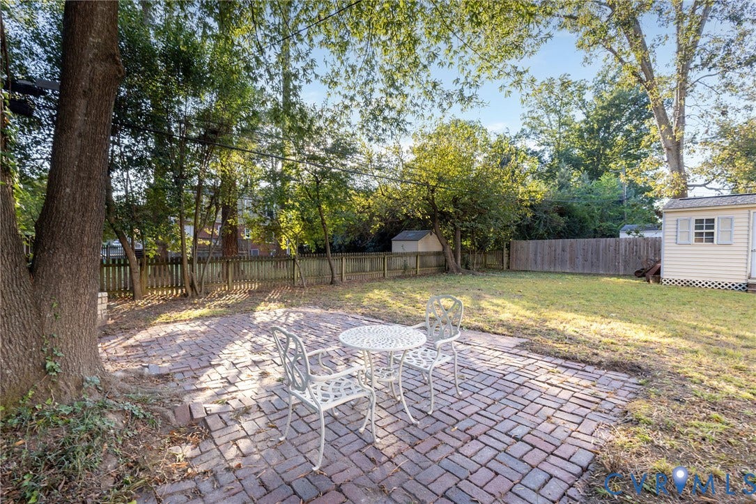 5211 W Grace Street, Richmond, VA 23226 Rear yard featuring a brick paver patio, wood-slat privacy fencing, a manicured lawn, and mature trees