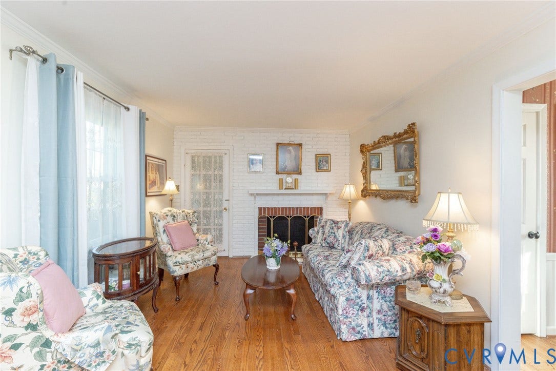 5211 W Grace Street, Richmond, VA 23226 Living area featuring white-painted brick fireplace with masonry hearth, wood-finish flooring, and multi-pane glass door