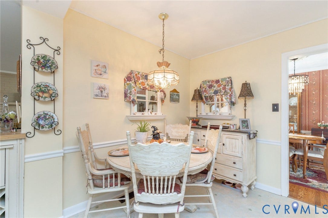 5211 W Grace Street, Richmond, VA 23226 Dining area featuring decorative chair rail molding, two multi-pane windows with integrated sills, and a brass-tone multi-light pendant fixture