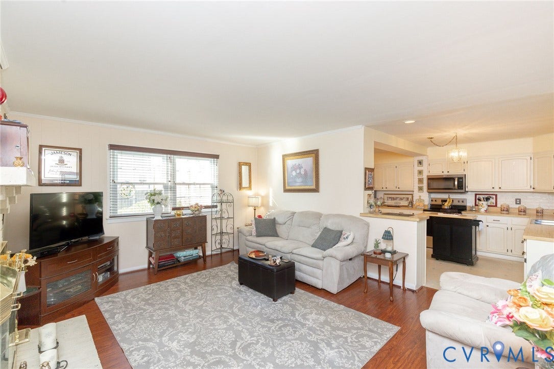 5211 W Grace Street, Richmond, VA 23226 Open-concept living space featuring wood-finish flooring, white cabinetry, integrated stainless steel appliances, and multi-pane windows