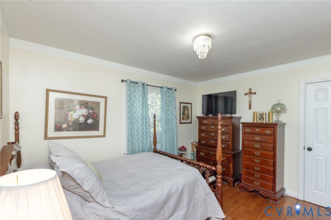 5211 W Grace Street, Richmond, VA 23226 Room featuring wood-finish flooring, a central crystal-style flush mount ceiling light, and a white six-panel interior door