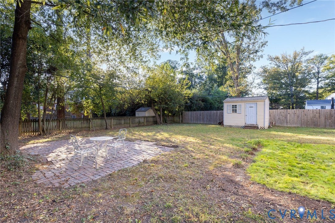 5211 W Grace Street, Richmond, VA 23226 Backyard featuring a brick paver patio, detached storage shed, perimeter wood fencing, and mature trees