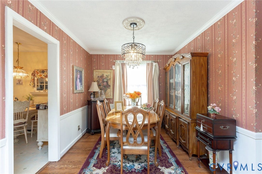 5211 W Grace Street, Richmond, VA 23226 Dining area featuring wood-finish flooring, patterned wallcovering, white wainscoting, crown molding, and a decorative crystal-style chandelier with a matching ceiling medallion