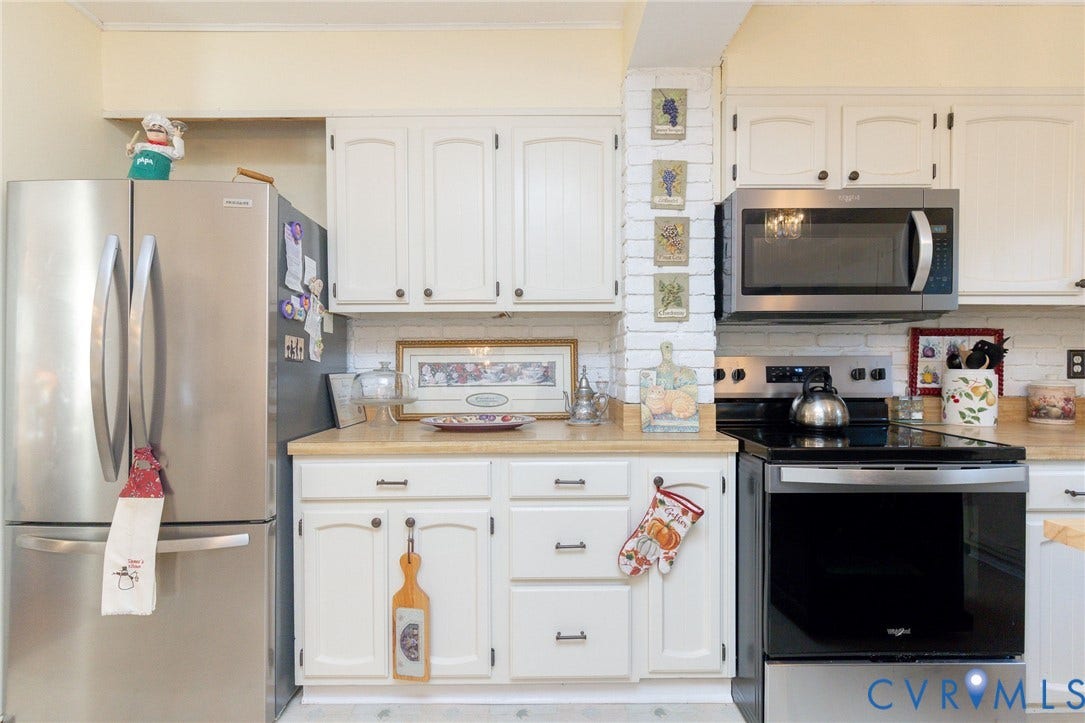 5211 W Grace Street, Richmond, VA 23226 Kitchen featuring white cabinetry, stainless steel appliances, solid-surface countertops, and a white brick-finish wall accent