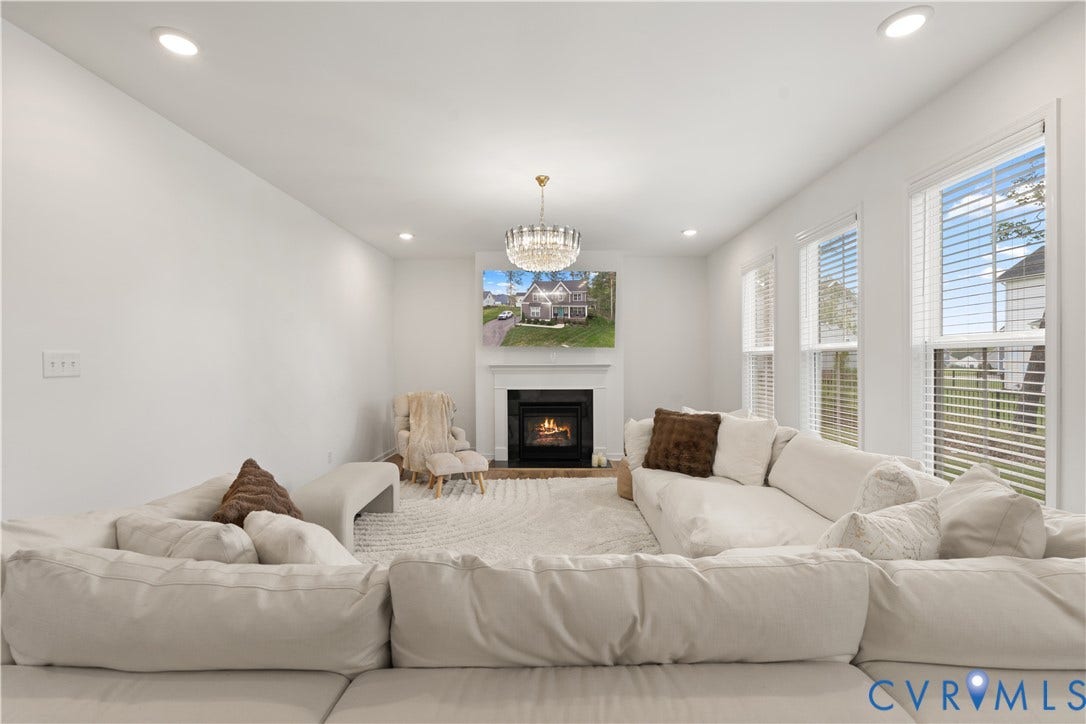 13807 Denleigh Court, Midlothian, VA 23112 Gas fireplace with white mantel, crystal chandelier, recessed lighting, and large windows with horizontal blinds