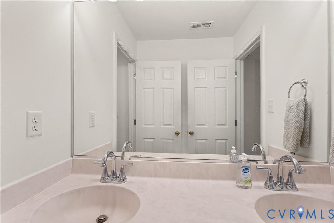 13807 Denleigh Court, Midlothian, VA 23112 Dual-sink vanity with solid-surface countertop, integrated basins, chrome fixtures, and a wall-to-wall mirror