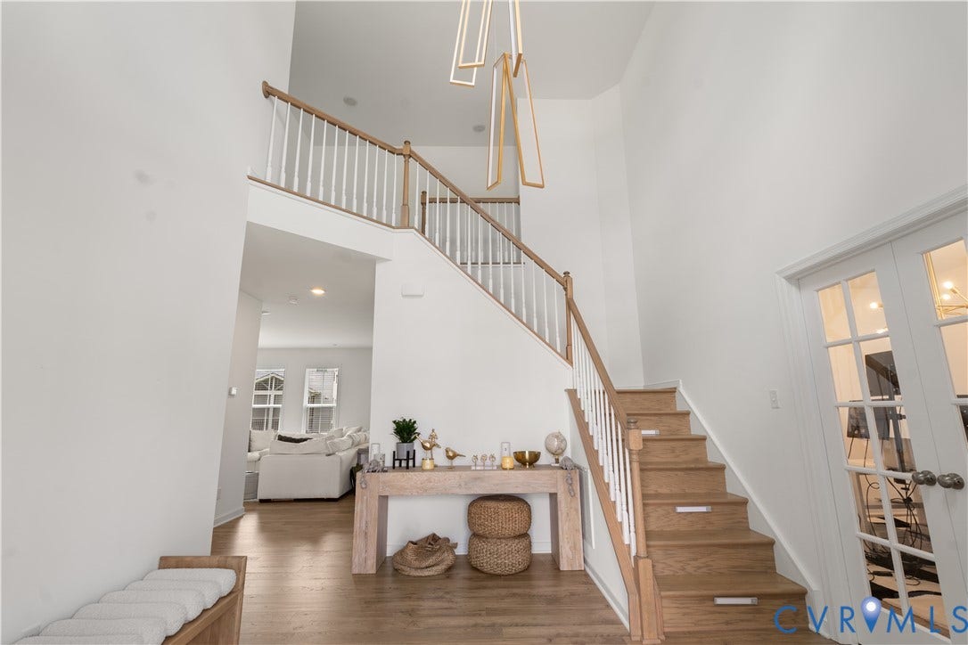 13807 Denleigh Court, Midlothian, VA 23112 Double-height foyer featuring wood-finish flooring, a contemporary geometric chandelier, and a staircase with a wooden handrail and white balusters