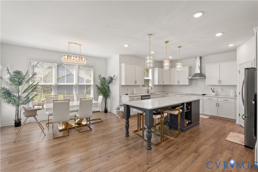 13807 Denleigh Court, Midlothian, VA 23112 Open-concept kitchen featuring wood-finish flooring, white shaker-style cabinetry, a central island with a contrasting dark base, quartz countertops, and stainless steel range hood