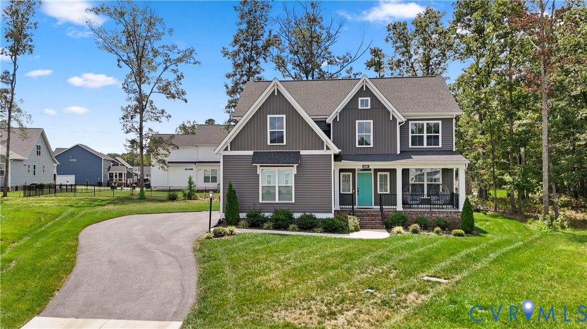 13807 Denleigh Court, Midlothian, VA 23112 Two-story residence featuring vertical dark-tone siding, a covered front porch with brick foundation, multi-gabled roofline, asphalt driveway, and mature perimeter trees
