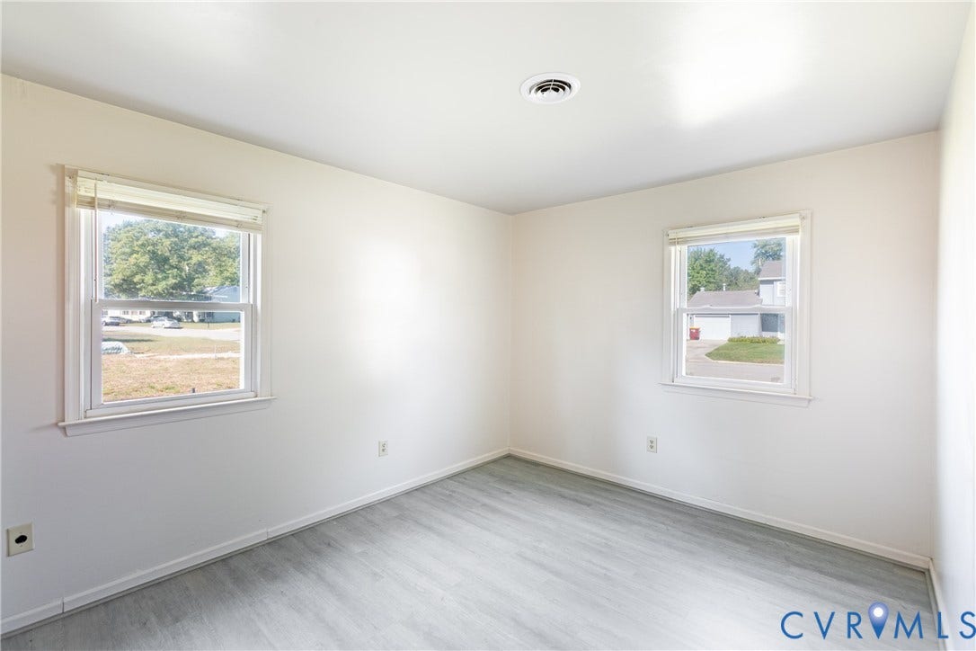 542 Petty Street, Petersburg, VA 23805 Neutral-toned interior room featuring wood-finish flooring, dual windows with white horizontal blinds, and smooth-finish walls