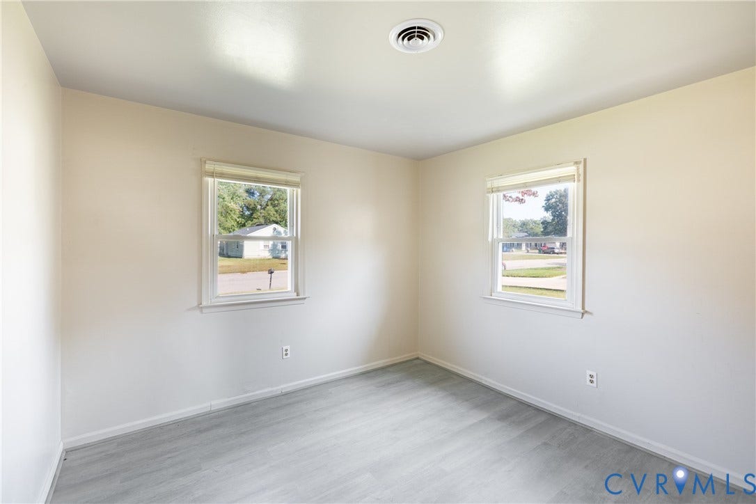 542 Petty Street, Petersburg, VA 23805 Neutral-toned interior space featuring light wood-finish flooring, two double-hung windows with white casing, and white walls