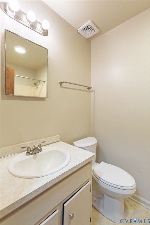 542 Petty Street, Petersburg, VA 23805 Vanity featuring a stone-patterned countertop, integrated oval basin, brushed-metal hardware, a wall-mounted rectangular mirror, and a three-light vanity fixture