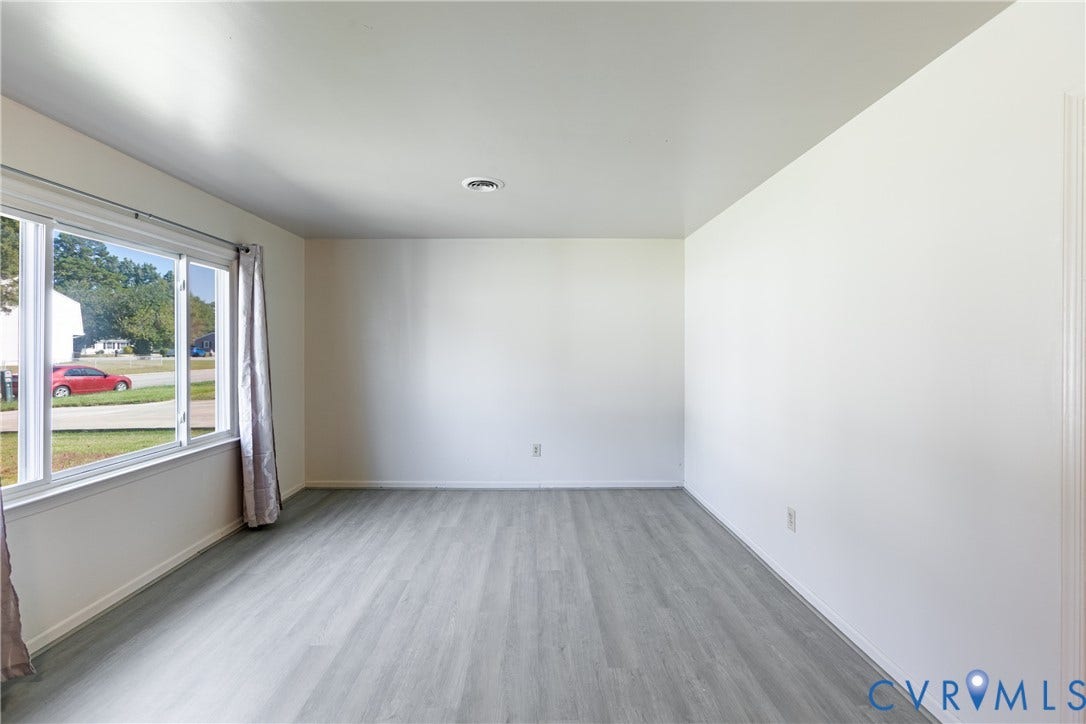 542 Petty Street, Petersburg, VA 23805 Neutral-toned interior space featuring wood-finish flooring, white walls, and a large multi-pane window