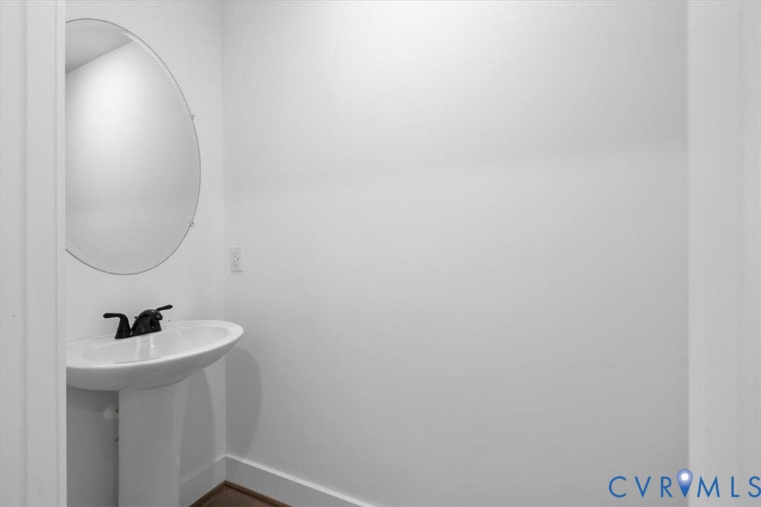 2242 Lakeview Drive, Powhatan, VA 23139 Pedestal sink featuring a white basin and matte black faucet, paired with a frameless oval wall-mounted mirror
