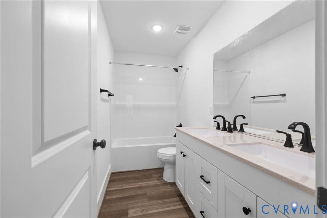 2242 Lakeview Drive, Powhatan, VA 23139 Dual-sink vanity with a light-toned countertop, matte black fixtures, wood-finish flooring, and a full-width mirror