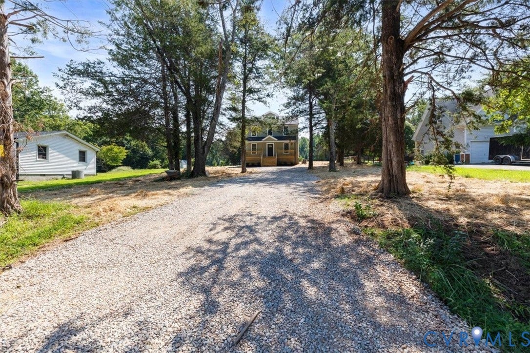 2242 Lakeview Drive, Powhatan, VA 23139 Gravel driveway approach leading to a two-story residence with a covered front porch and mature tree-lined grounds