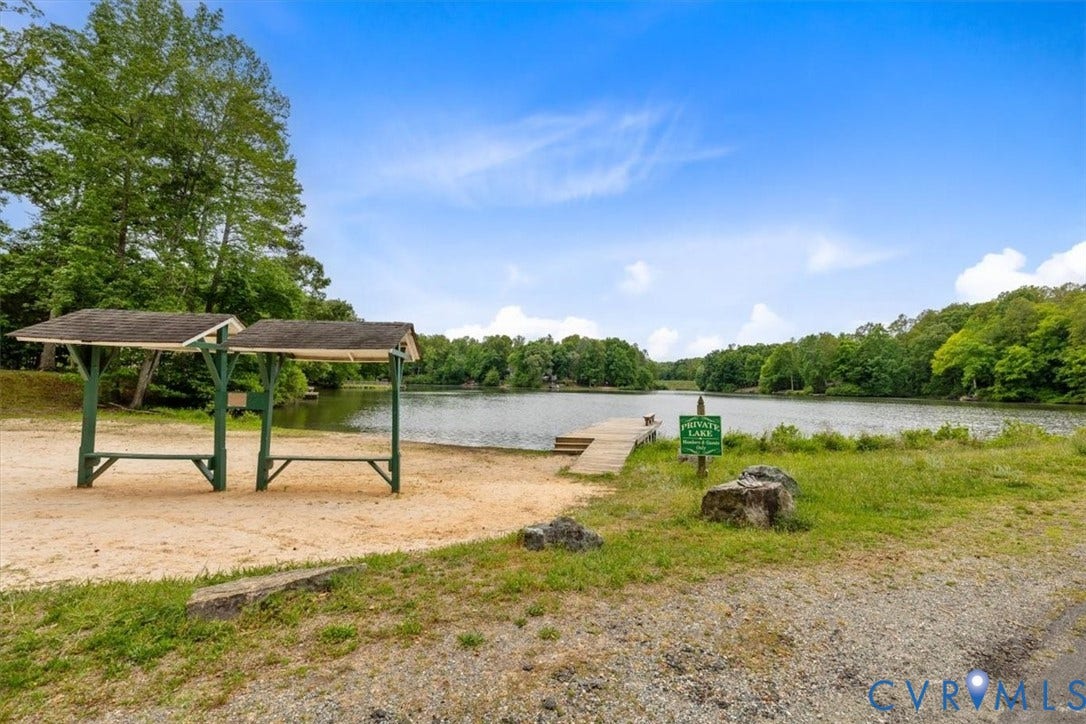 2242 Lakeview Drive, Powhatan, VA 23139 Waterfront property featuring a private lake, a wood-framed dock, and two permanent shaded structures situated on a sandy shoreline