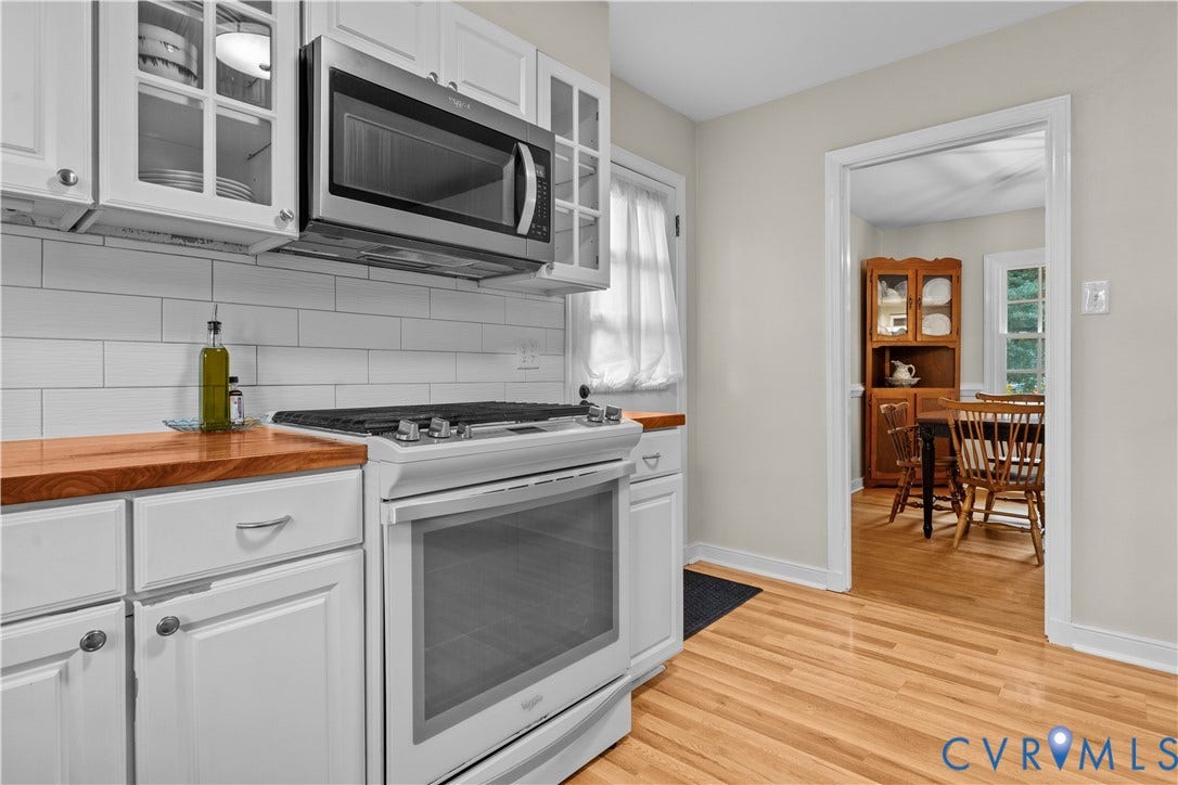 6956 Old Westham Road, Stratford Hills/Cherokee Road, Richmond, VA 23225 Kitchen featuring white cabinetry with glass-panel inserts, butcher-block countertops, a white subway-tile backsplash, stainless steel over-the-range microwave, and wood-finish flooring