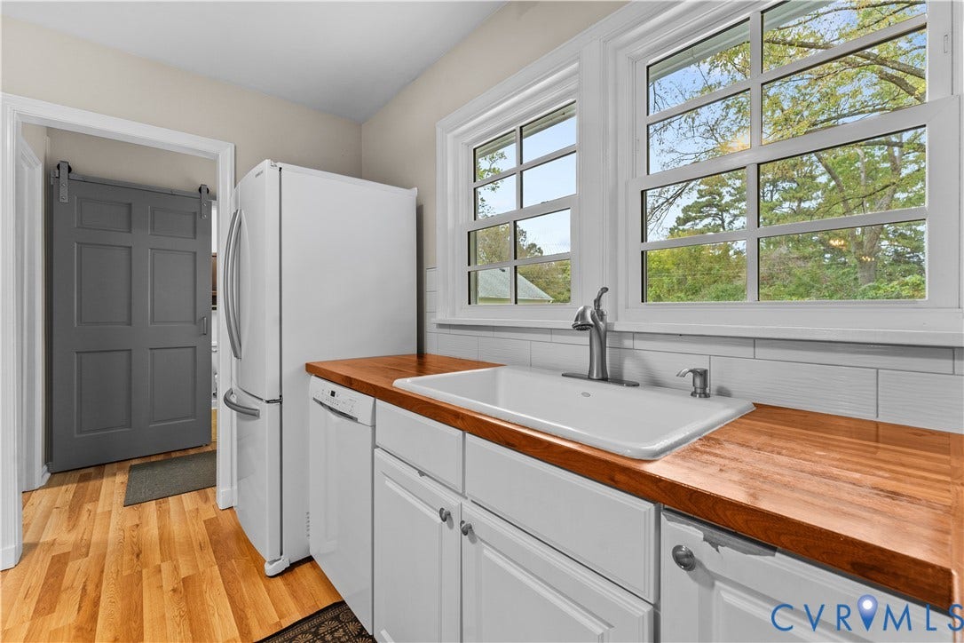 6956 Old Westham Road, Stratford Hills/Cherokee Road, Richmond, VA 23225 Kitchen featuring white cabinetry, wood countertops, a farmhouse-style apron sink, white tile backsplash, and a gray sliding barn door