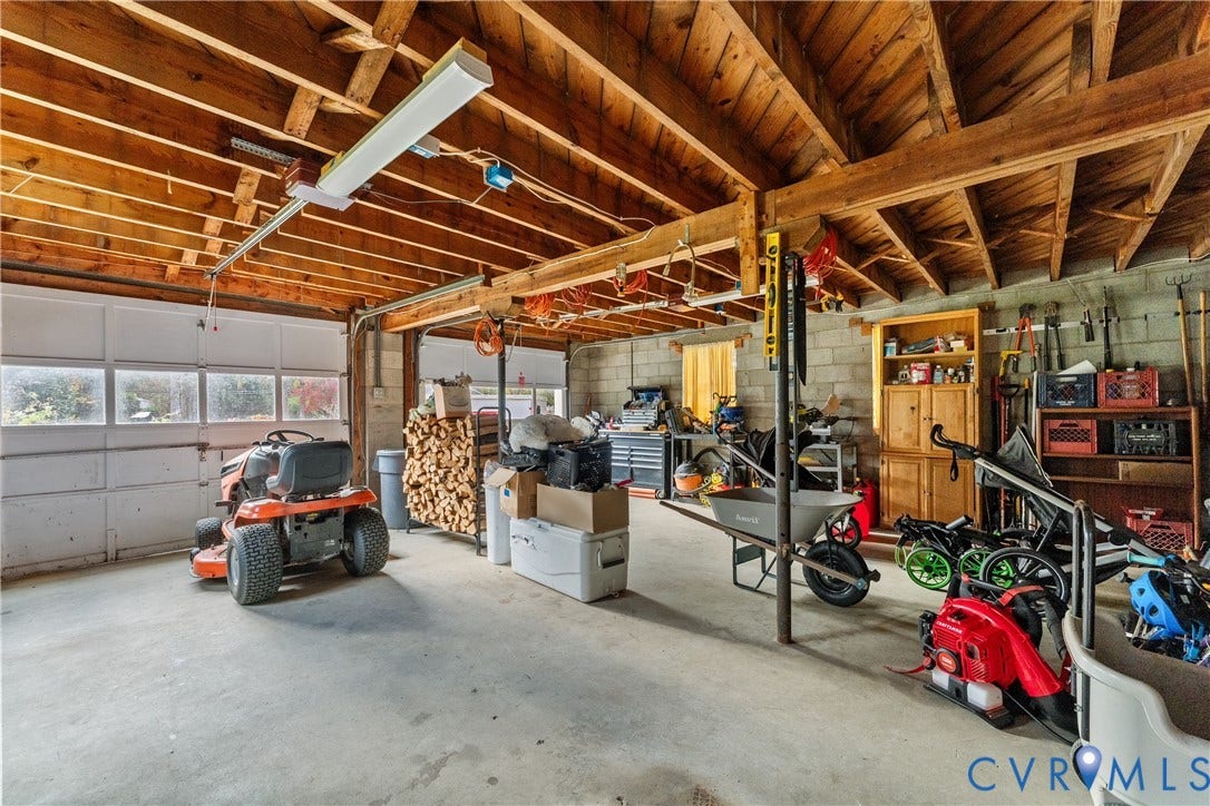 6956 Old Westham Road, Stratford Hills/Cherokee Road, Richmond, VA 23225 Garage featuring exposed wooden rafters, concrete flooring, concrete masonry unit walls, built-in wooden shelving, and a paneled garage door