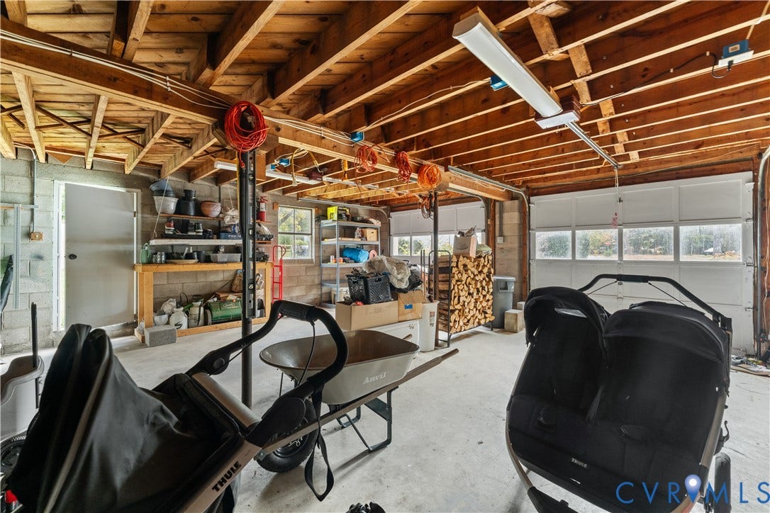 6956 Old Westham Road, Stratford Hills/Cherokee Road, Richmond, VA 23225 Garage space featuring exposed timber ceiling joists, concrete flooring, concrete block walls, and multi-panel overhead garage doors with rectangular glass panes