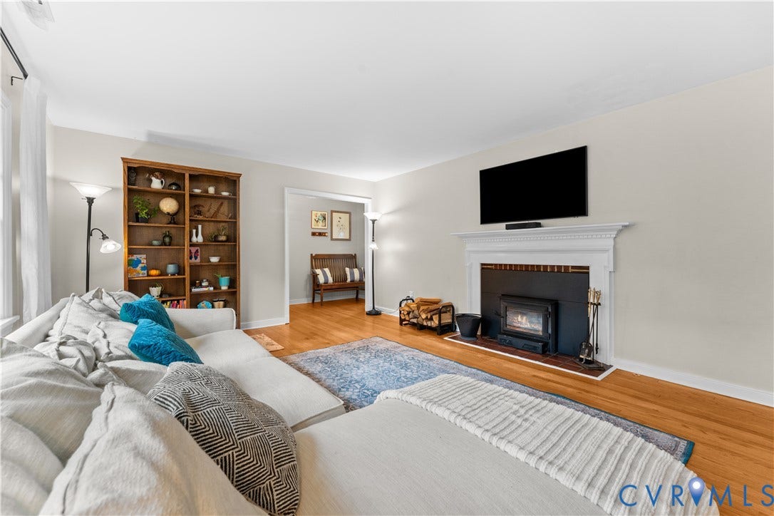 6956 Old Westham Road, Stratford Hills/Cherokee Road, Richmond, VA 23225 Living area featuring wood-finish flooring, a built-in wooden bookshelf, and a white mantel fireplace with a black insert