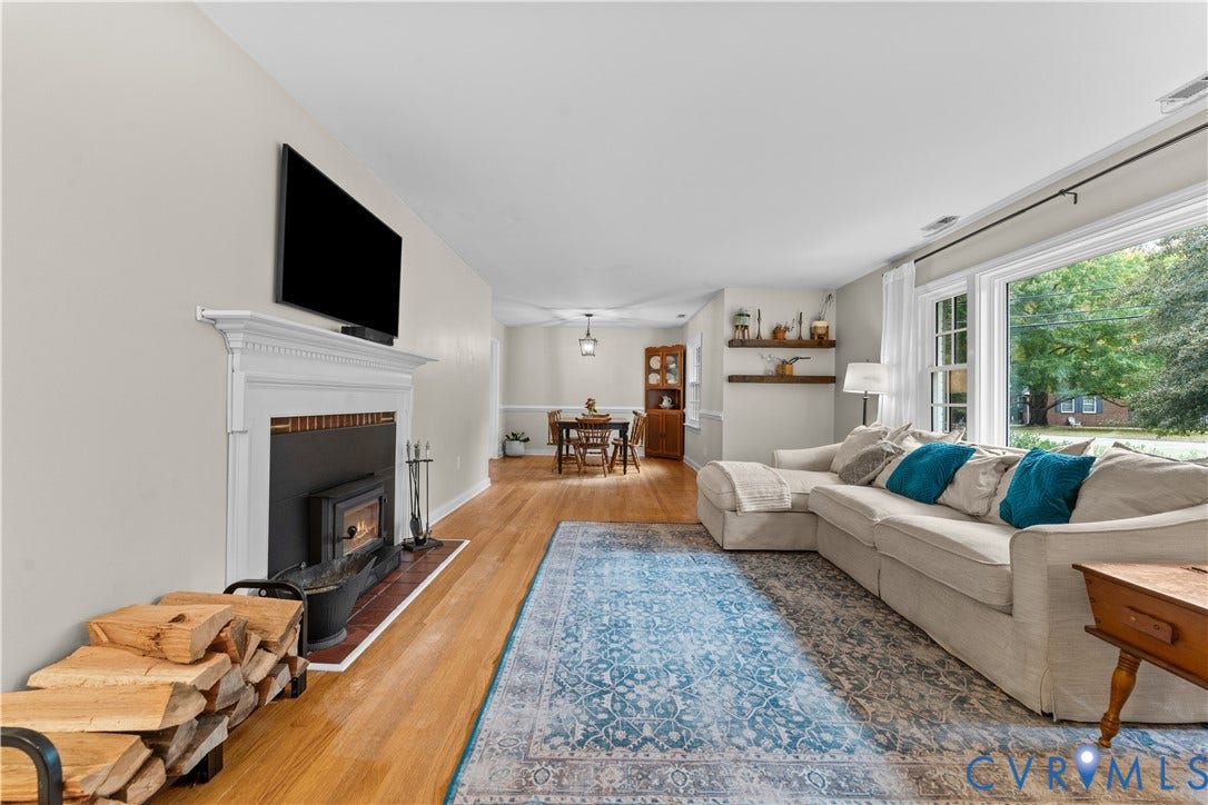 6956 Old Westham Road, Stratford Hills/Cherokee Road, Richmond, VA 23225 Living area featuring wood-finish flooring, a fireplace with a white mantel, built-in wooden wall shelving, and a large picture window