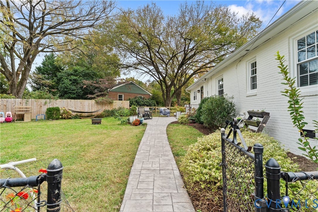 6956 Old Westham Road, Stratford Hills/Cherokee Road, Richmond, VA 23225 Spacious backyard featuring a stamped concrete walkway, painted brick exterior, wooden privacy fencing, and mature trees