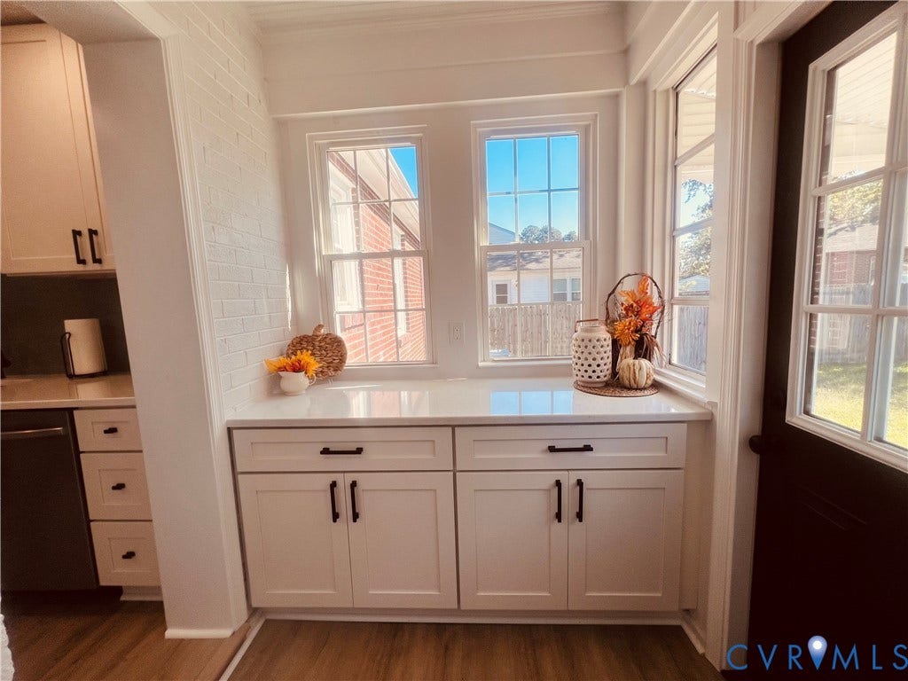 404 Ivey Avenue, Woodlawn, Colonial Heights, VA 23834 Built-in white cabinetry featuring shaker-style doors, matte black hardware, and solid surface countertops, accented by painted brick walls and multi-pane windows