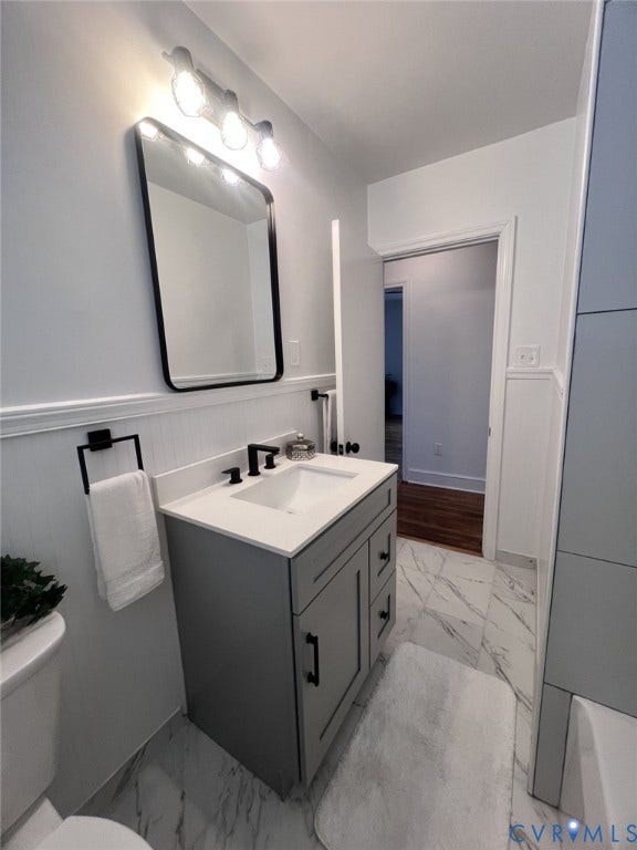 404 Ivey Avenue, Woodlawn, Colonial Heights, VA 23834 Modern vanity featuring a stone-composite countertop, rectangular undermount sink, matte black hardware, vertical wainscoting, and marble-finish tile flooring